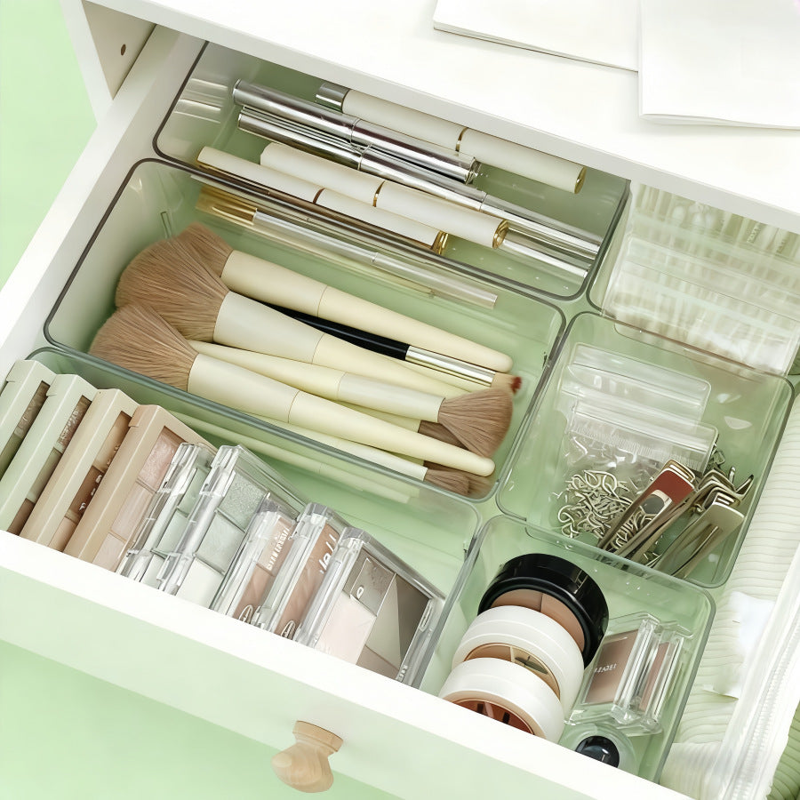 Clear bins in a drawer holding makeup brushes and cosmetics