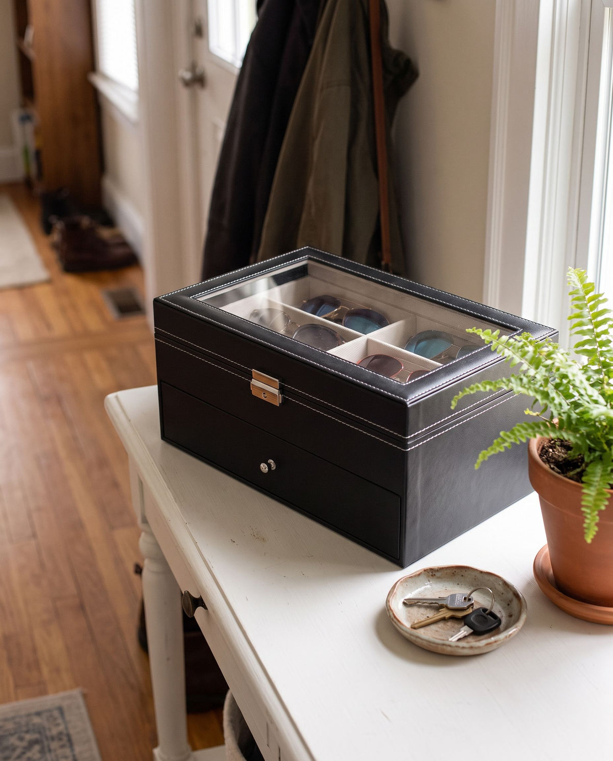 Eyewear organizer closed on an entryway console, sunglasses visible through the glass lid (eyewear not included)