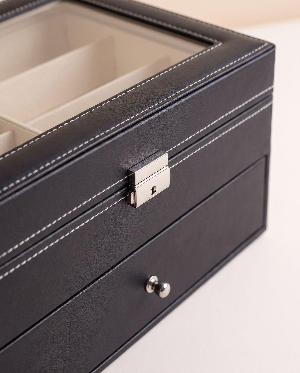 Close detail of the eyewear organizer lid lock, stitching and lower drawer