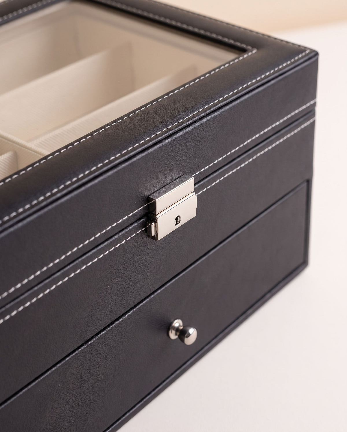 Close detail of the eyewear organizer lid lock, stitching and lower drawer