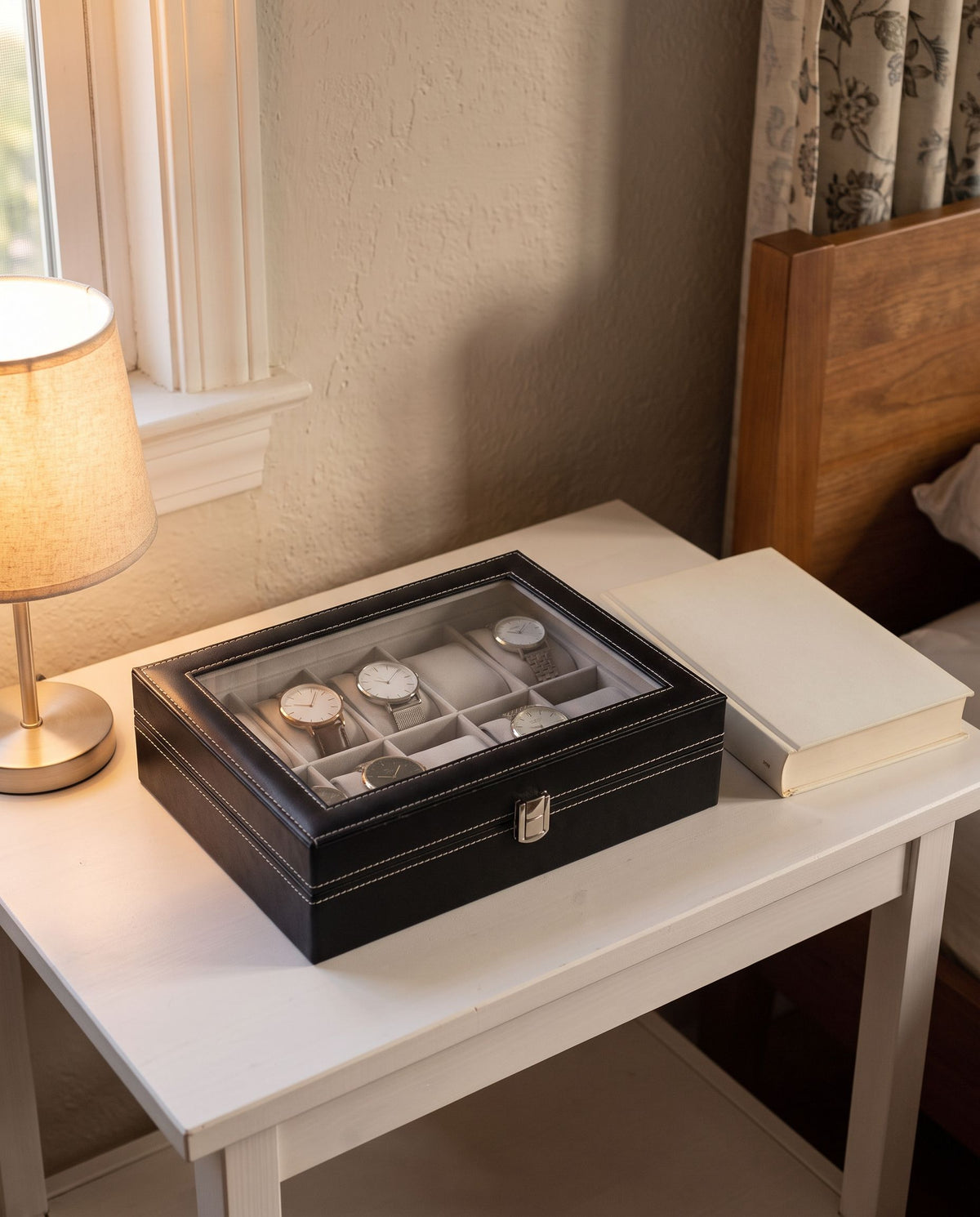 12-slot watch case closed on a nightstand, watches visible through the window lid (watches not included)