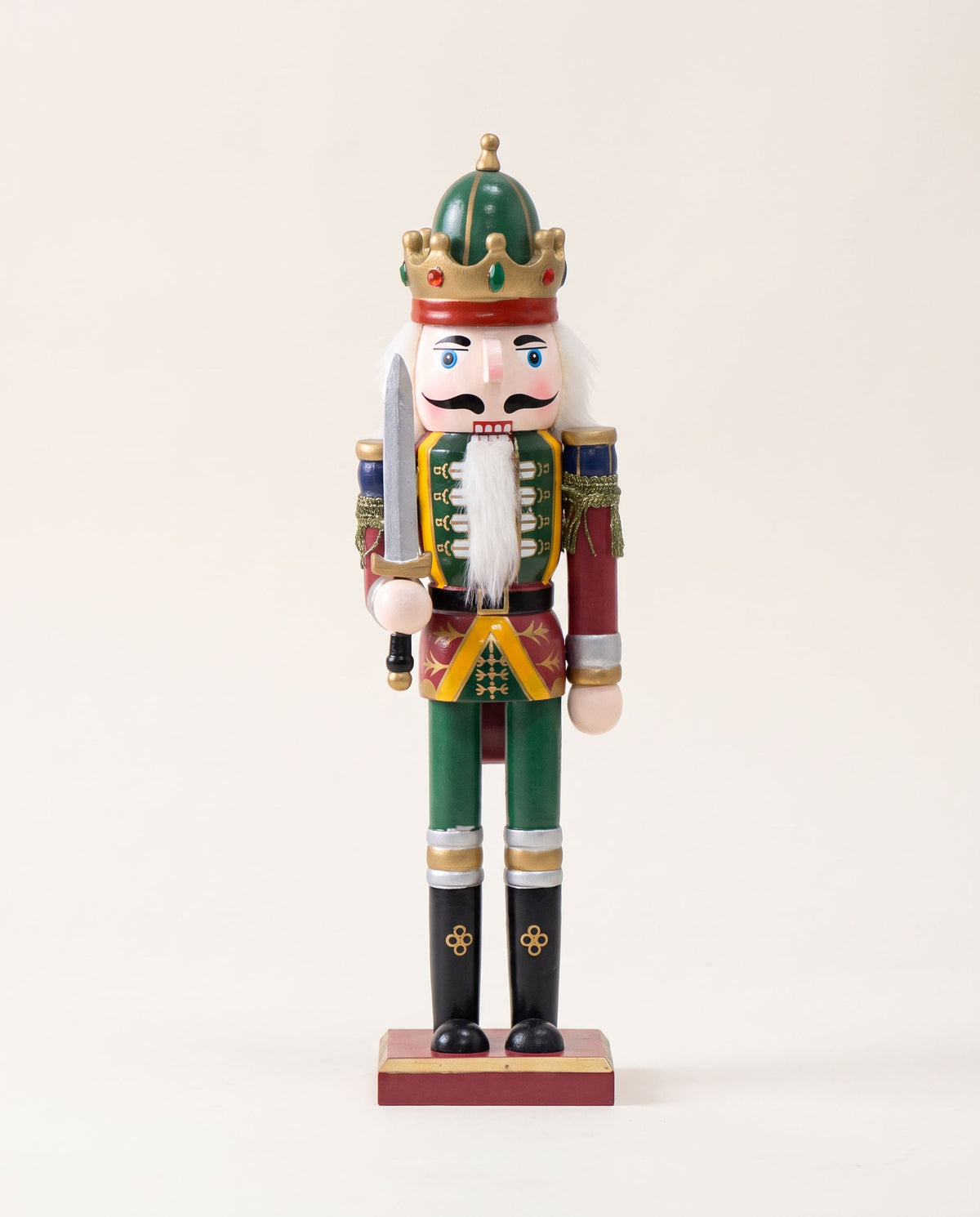Wooden nutcracker soldier with green crown, white beard, red coat, green trousers and sword on a red base