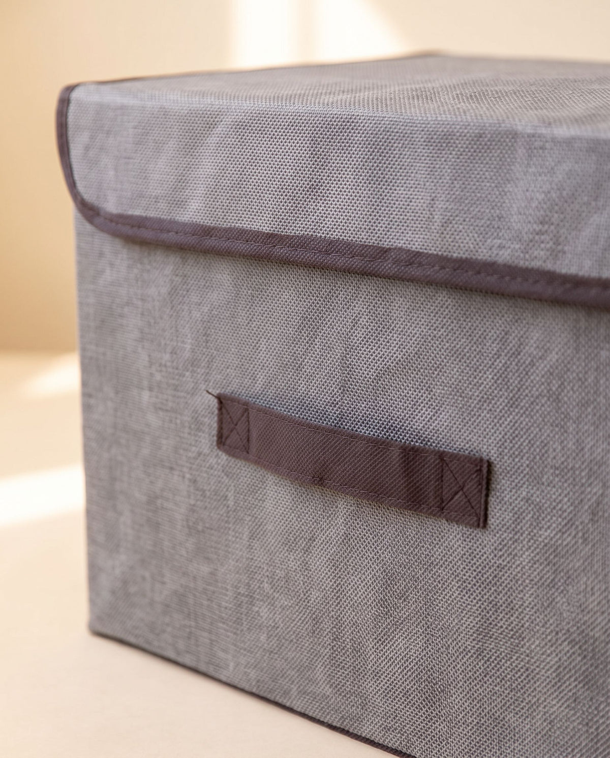 Close detail of the storage box front strap handle and trimmed lid edge