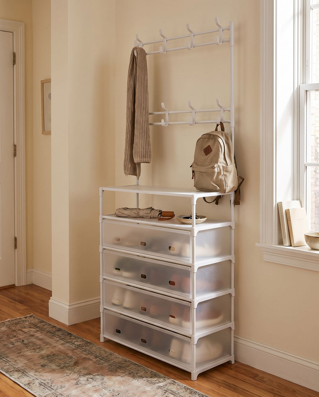 White hall tree in an apartment hallway with a scarf and backpack on the hooks (items not included)