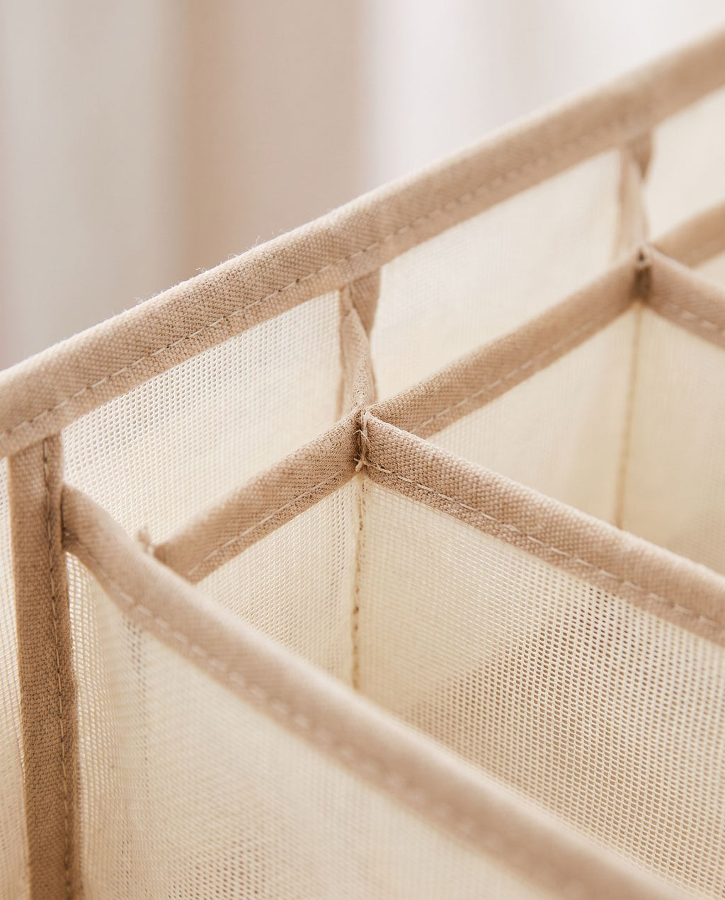 Close detail of the beige mesh compartment walls and stitched binding