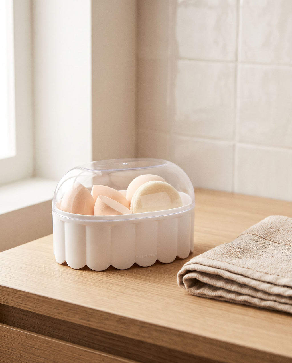 The box on a bathroom vanity with sponges visible through the clear lid